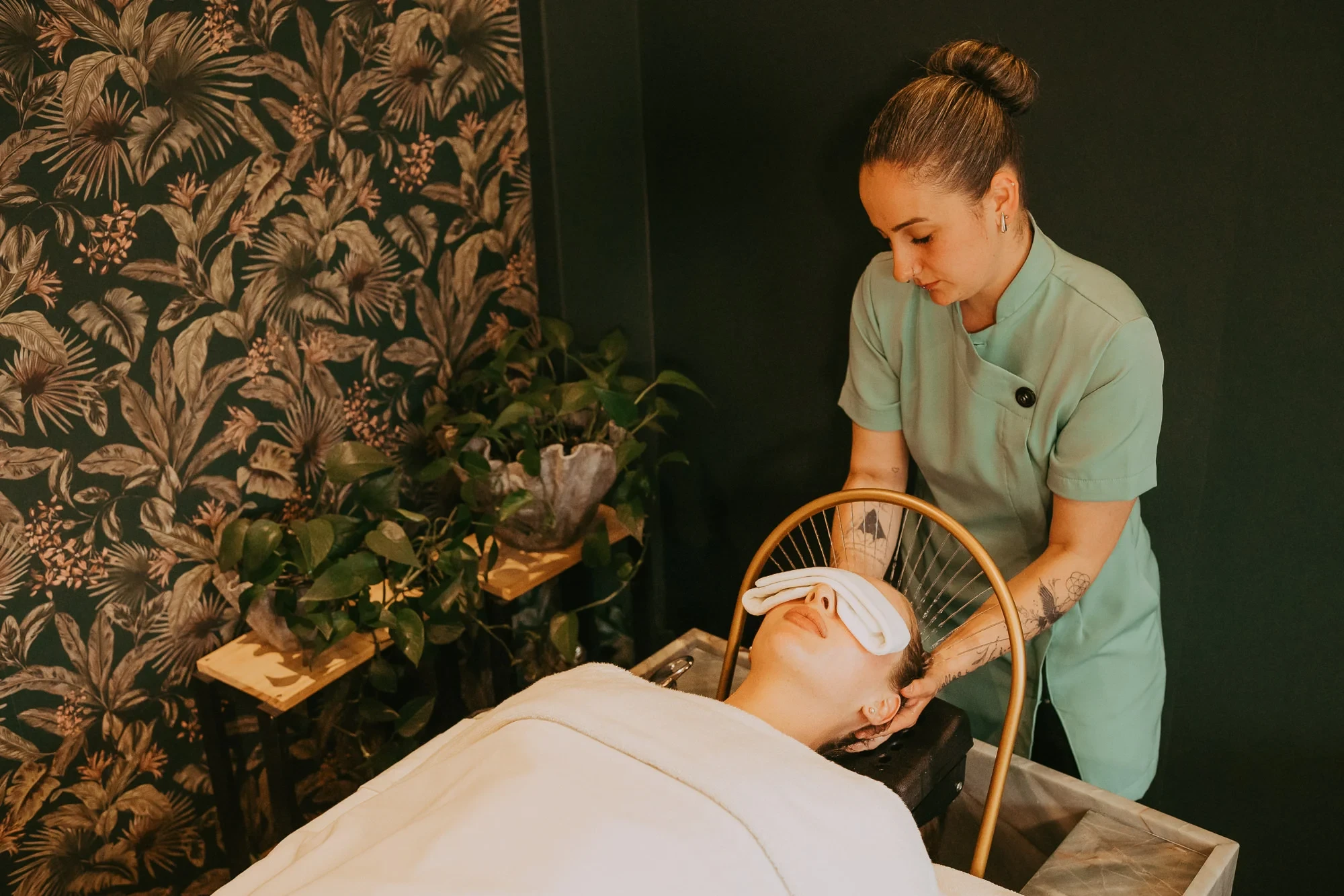 Terapeuta do Morada SPA durante o Head Spa, em sala com papel de parede de folhagens